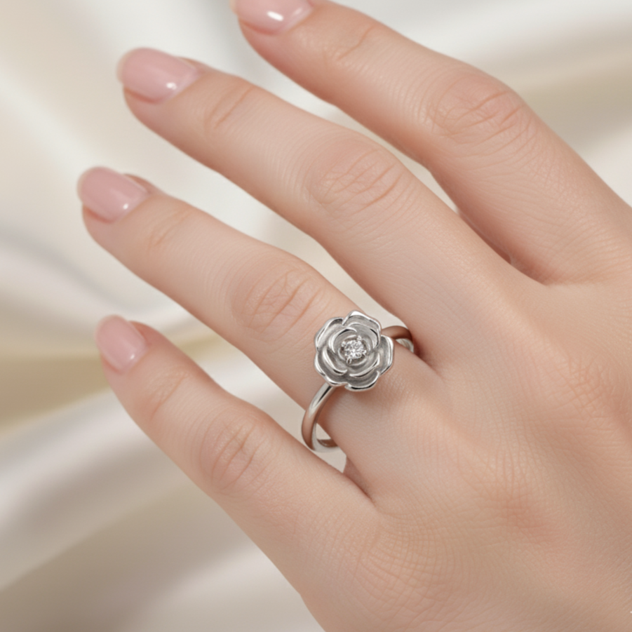 Silver rose-shaped ring on a hand against a soft background
